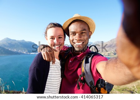 Portrait of smiling young couple on vacation taking selfie with mobile phone