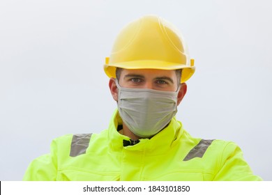 Portrait Of Smiling Young Engineer With Face Mask And Hard Hat And Protective Work Wear