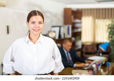 Portrait Of A Smiling Young Female Employee Standing In A Well-lit Office Of A Large Company. Close-up Portrait