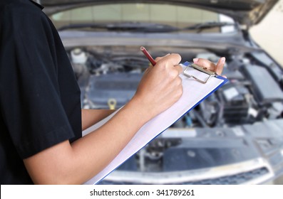 Portrait of smiling young female mechanic inspecting on a car in auto repair shop - Powered by Shutterstock