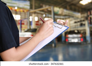 Portrait of smiling young female mechanic inspecting on a car in auto repair shop