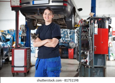 Portrait of smiling young female mechanic with arms crossed in auto repair shop - Powered by Shutterstock