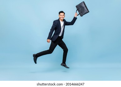 Portrait of smiling young handsome Asian male office worker running in mid-air holding bag in light blue isolated studio background - Shutterstock ID 2014666247