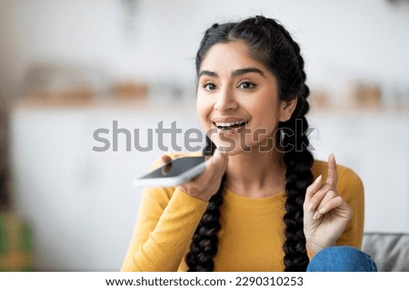 Portrait Of Smiling Young Indian Female Recording Voice Message On Smartphone While Resting At Home, Happy Eastern Woman Using Virtual Assistant On Mobile Phone, Enjoying Modern Technologies