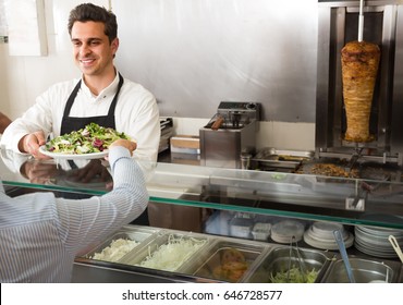 Portrait Of A Smiling Young Male Fast Food Worker At Counter Of Kebab Cafe