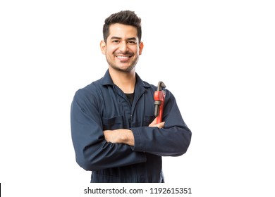 Portrait of smiling young male plumber with pipe wrench standing arms crossed on white background - Powered by Shutterstock