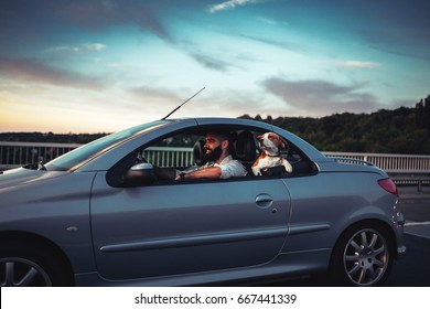 Portrait Of A Smiling Young Man Enjoying Riding In The Car With A Dog.