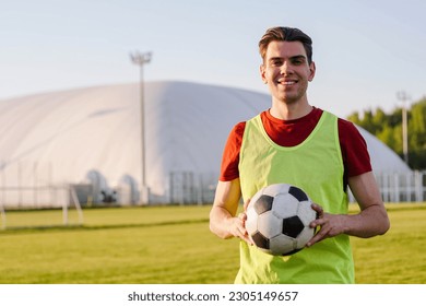 Portrait of a smiling young man football player with a soccer ball at sunset, copy space - Powered by Shutterstock