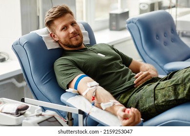 Portrait Of Smiling Young Man Giving Blood At Donor Center In Comfort While Lying In Chair, Copy Space