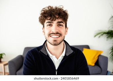 Portrait of smiling young man looking at camera standing at home. Head shot of millennial happy male.