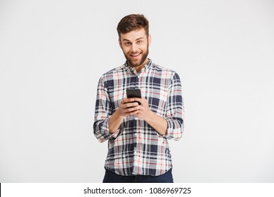 Portrait of a smiling young man in plaid shirt holding mobile phone isolated over white background - Powered by Shutterstock