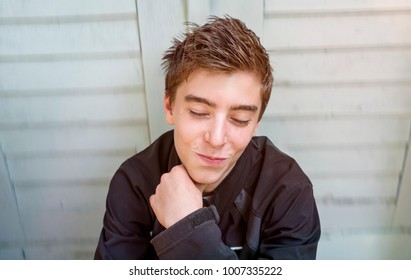 Portrait of a smiling young man sitting in front of a door