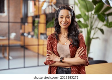 Portrait of smiling young multiethnic woman looking at camera with crossed arms. Successful latin business woman standing in modern office with copy space. Young university hispanic girl with smile. - Shutterstock ID 2318383273