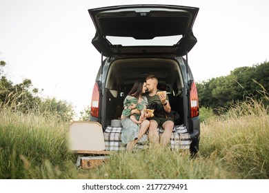 Portrait Of Smiling Young Parents Embarrassing Their Little Daughter And Dog With Delicious Pizza. Happy Family Of Three Having Weekend Party On Fresh Air.