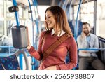 Portrait of smiling young passenger woman buying bus ticket on ticket machine in public transportation.