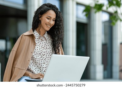 Portrait of a smiling young professional woman using a laptop in an urban outdoor setting, exuding confidence and positivity. - Powered by Shutterstock