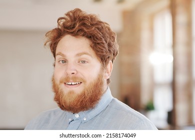 Portrait Of Smiling Young Red Bearded Man With Curly Hair Standing In Office Of Modern Company