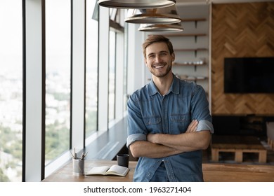 Portrait of smiling young successful Caucasian businessman stand pose in modern office show leadership. Happy man employee or worker feel motivated confident at workplace. Recruitment concept.