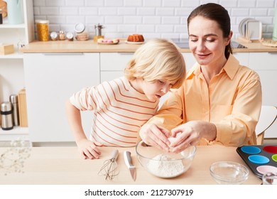 Portrait Of Smiling Young Woman Baking Cupcakes With Cute Little Boy Helping Mom