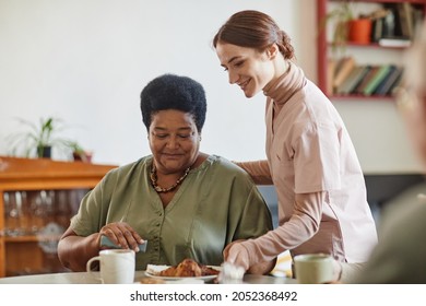 Portrait Of Smiling Young Woman Caring For Senior African-American Lady In Nursing Home, Copy Space