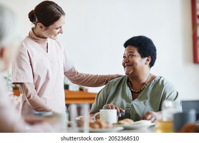 Portrait Of Smiling Young Woman Caring For Senior African-American Patient In Nursing Home, Copy Space