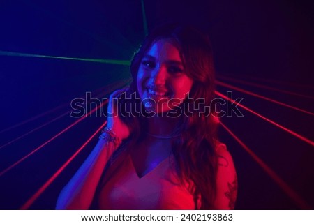 Portrait of smiling young woman dancing in neon lights of night club