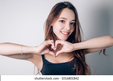 Portrait Of Smiling Young Woman With Heart Shape Hand Sign