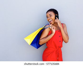Portrait of smiling young woman holding shopping bags talking on cell phone