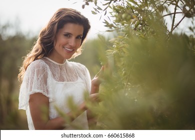 Portrait of smiling young woman holding olive tree at farm - Powered by Shutterstock