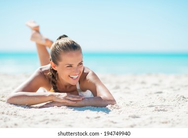 Portrait of smiling young woman laying on beach and looking on copy space - Powered by Shutterstock