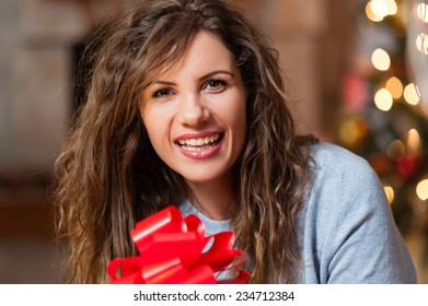 Portrait Of Smiling Young Woman Near Christmas Tree Over Living Room.