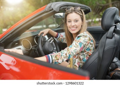 Portrait Of Smiling Young Woman In Red Convertible Car