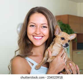 Portrait Of Smiling Young Woman With Russian Toy In Arms At Home 