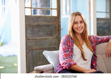Porträt von lächelnden jungen Frauen, die zu Hause auf Sofa sitzen