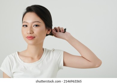 Portrait Of Smiling Young Woman Twisting Hair When Making Elegant Bun