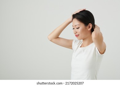 Portrait Of Smiling Young Woman Twisting Hair When Making Small Elegant Bun