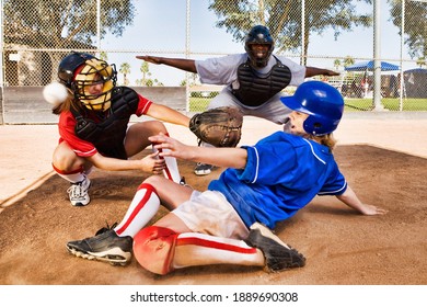 Portrait Of Softball Player Sliding Into Home Plate While Umpire Rules Safe