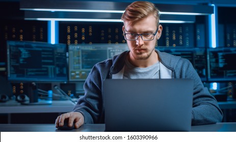 Portrait Of Software Developer / Hacker Wearing Glasses Sitting At His Desk And Working On Computer In Digital Identity Cyber Security Data Center. Hacking Or Programming.