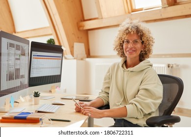 Portrait Of Software Developer Sitting At Her Workplace Witn Computers And Smiling At Camera At Office