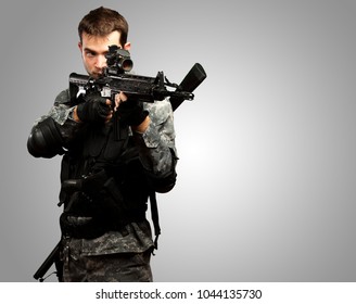 Portrait Of A Soldier Holding Gun against a grey background