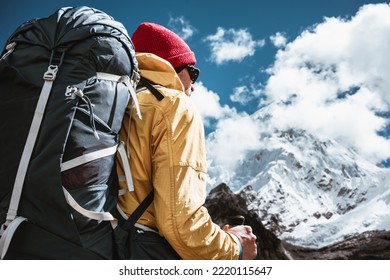 Portrait of solo hiker with traveling backpack standing in front of massive snowy mountains. Tourist among himalayas mountain going along rocky landscape - Powered by Shutterstock