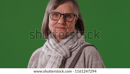 Portrait of somber elderly woman looking at camera on green screen