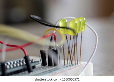 A portrait of a some electronics, it is a bread board with some LED's attached onto it, with some wires.
