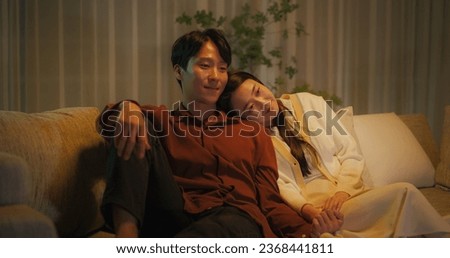 Portrait of a South Korean Couple Watching Romantic Comedy Movie on TV. Happy Boyfriend and Girlfriend Enjoying Funny Television Series Together at Home, Sitting Together on a Couch Late at Night