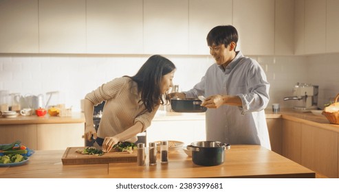 Portrait of a South Korean Young Couple Cooking at Home. Loving Boyfriend and Girlfriend Preparing Dinner in the Kitchen, Having a Funny Conversation While Cooking Delicious Food - Powered by Shutterstock