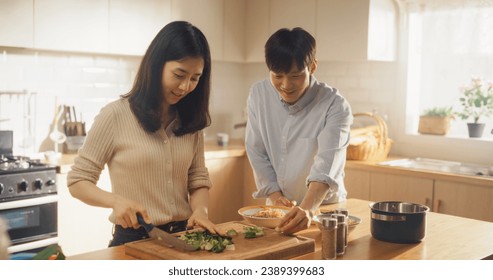 Portrait of a South Korean Young Couple Cooking at Home. Loving Boyfriend and Girlfriend Preparing Dinner in the Kitchen, Having a Funny Conversation While Cooking Delicious Food - Powered by Shutterstock