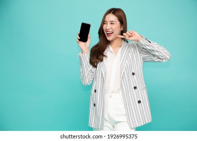 Portrait of Southeast Asian business woman showing or presenting mobile phone application on hand isolated on green background, One person of horizontal orientation, Blank screen smartphone concept - Powered by Shutterstock