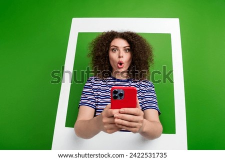 Portrait of speechless impressed person inside album set card stare hold smart phone isolated on green color background