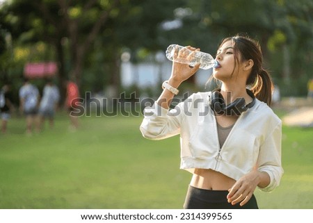 Portrait sport asian beauty body slim woman drinking water from a bottle while relax and feeling fresh, refresh drink, wellness, healthcare, mineral at green park.Healthy liquid lifestyle concept