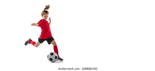 Portrait of sportive child, girl in red uniform playing, training football isolated over white background. Concept of action, sportive lifestyle, team game, health, energy, vitality and ad